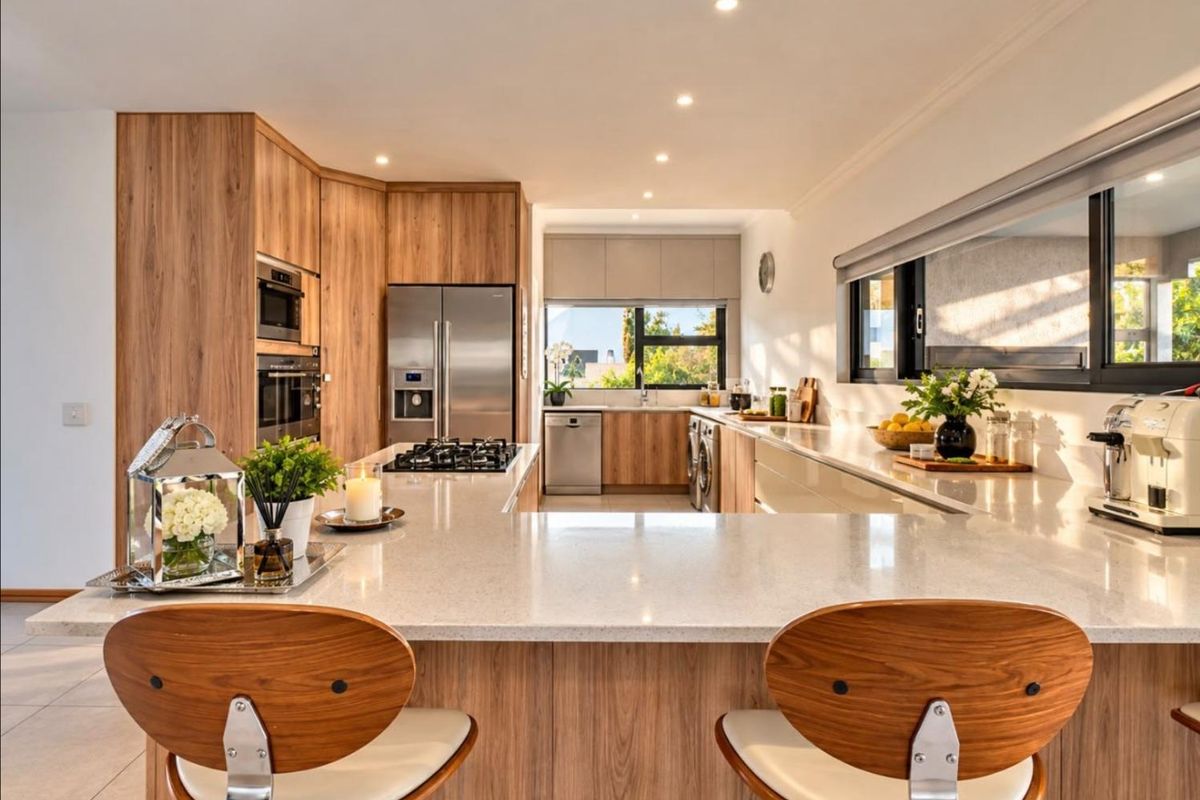 Modern, well-appointed kitchen featuring wood-grain cabinetry, stone countertops, high-end built-in appliances, and a spacious breakfast bar island.