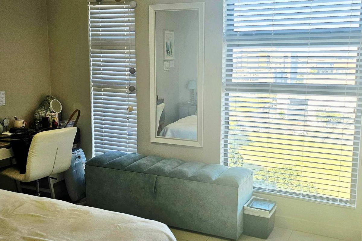 A bedroom featuring large windows with fitted horizontal blinds, providing natural light and views of the surrounding area.
