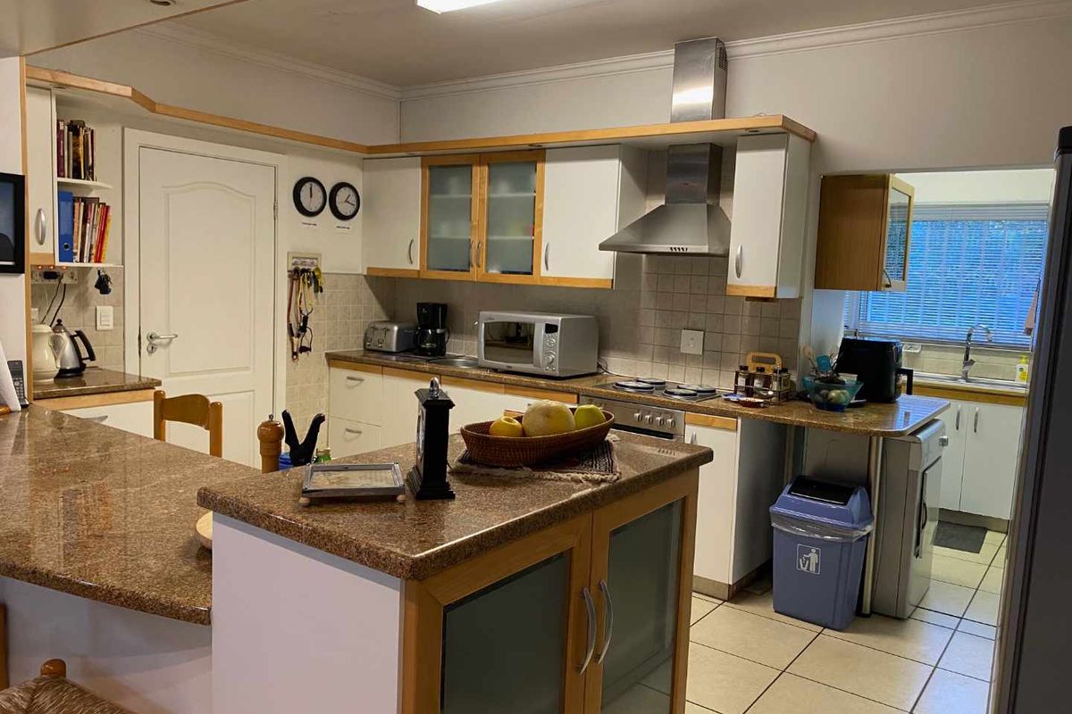 A functional kitchen featuring granite countertops, built-in cabinetry, a stainless steel extractor fan, and a breakfast bar island.