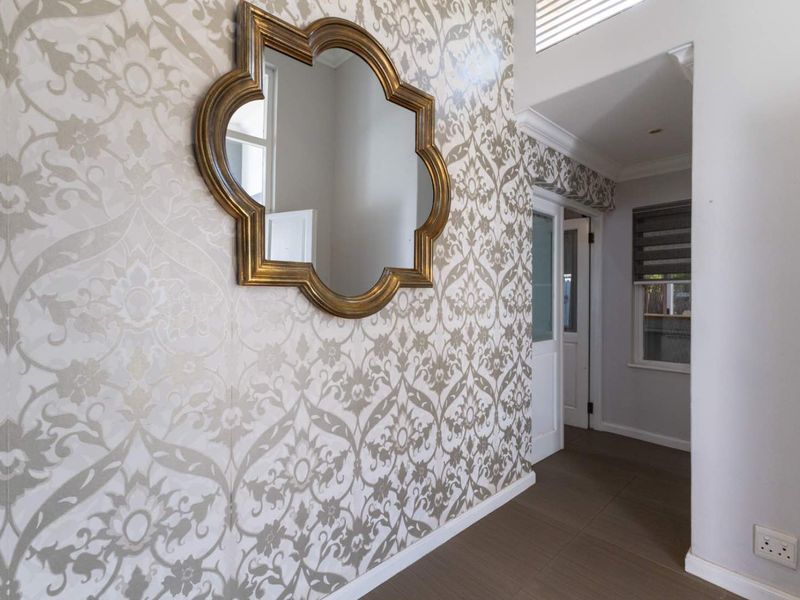 A bright and well-maintained hallway featuring decorative patterned wallpaper, tiled flooring, and clean architectural finishes.