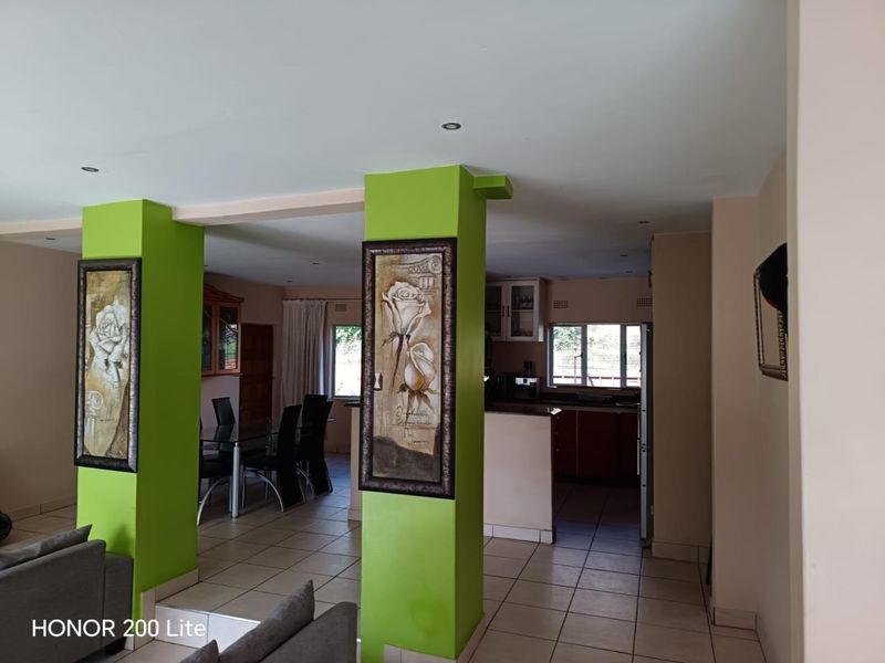 Open plan living and kitchen area featuring tiled flooring, structural columns, and recessed lighting, offering a functional layout for modern living.