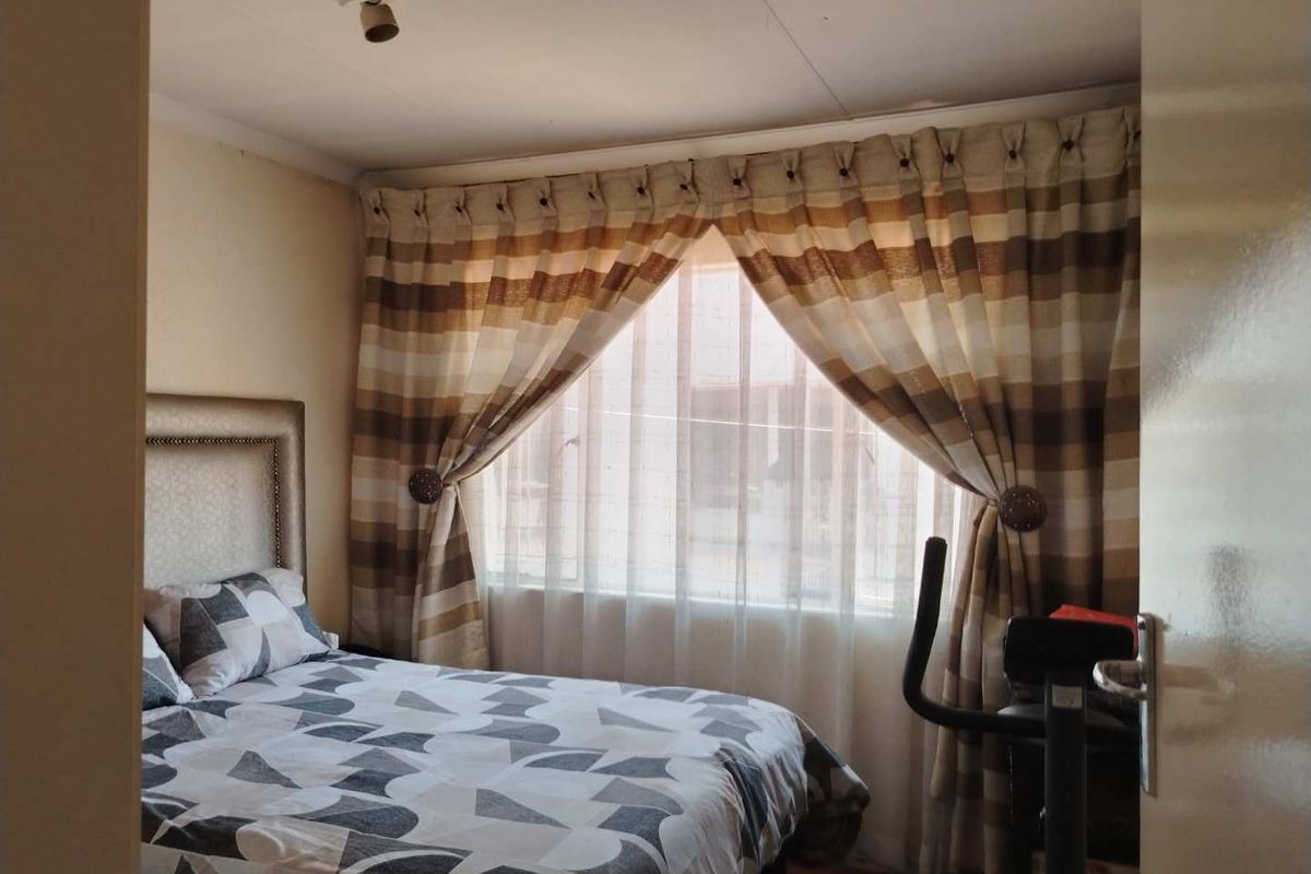 A bedroom featuring a window with curtains and a ceiling-mounted light fixture.
