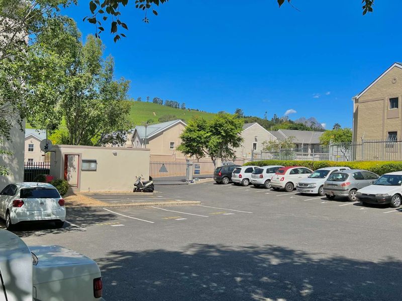A well-maintained paved parking area within a secure residential apartment complex, featuring perimeter fencing and gated access.