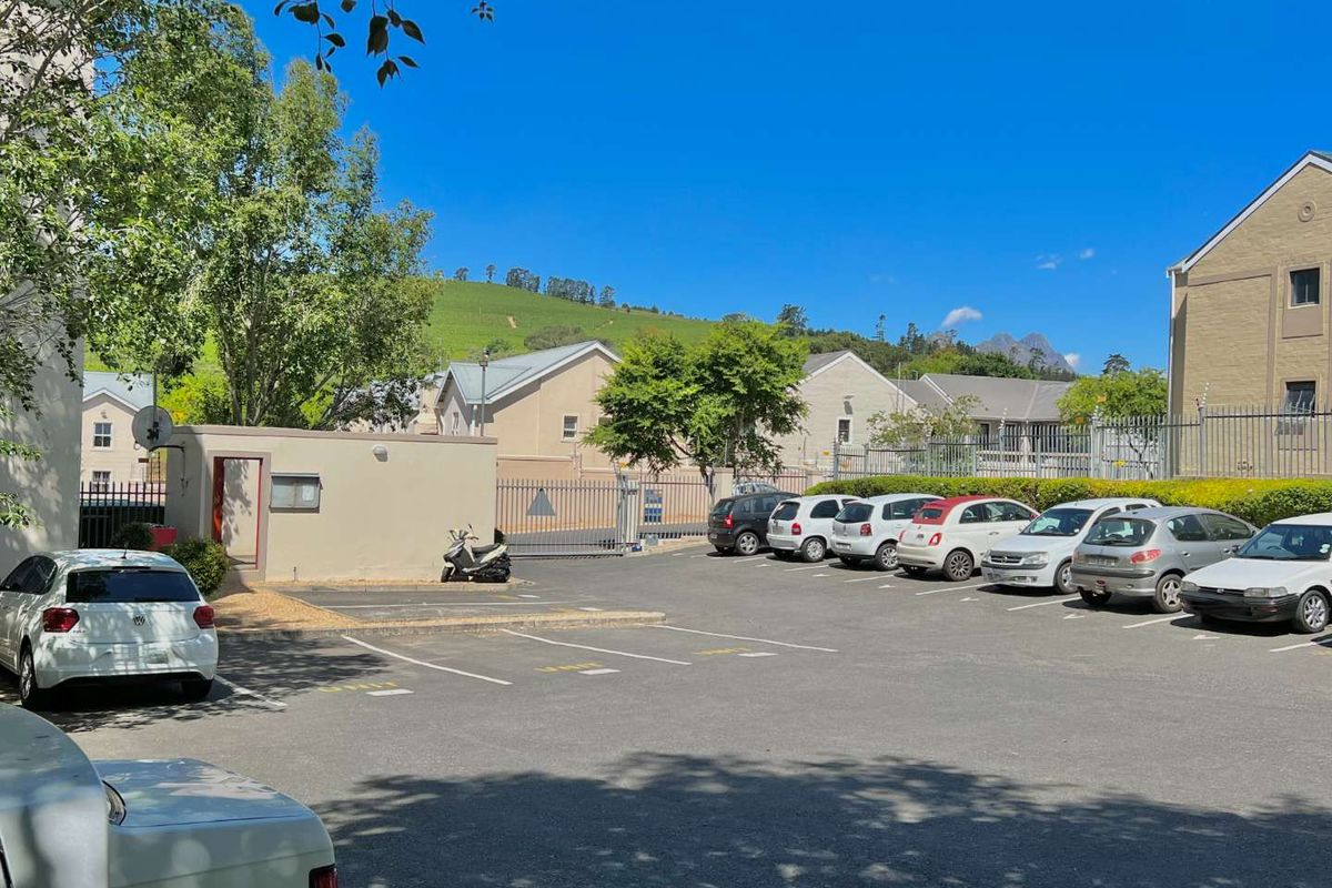A well-maintained paved parking area within a secure residential apartment complex, featuring perimeter fencing and gated access.