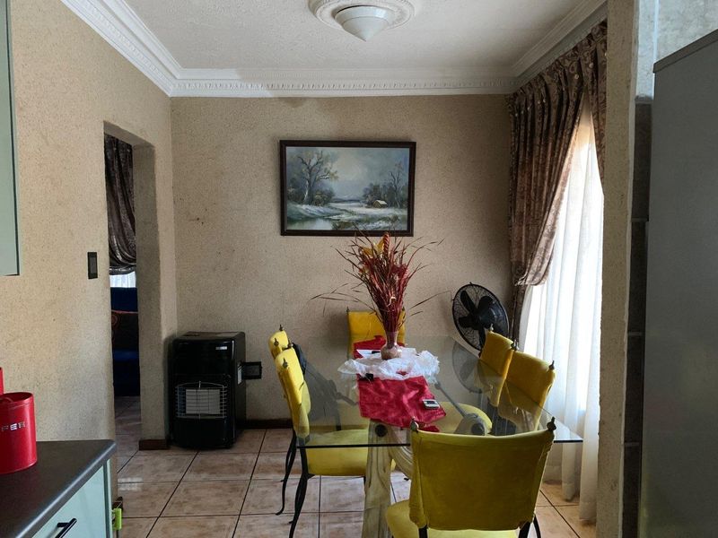 A dining room featuring tiled flooring, decorative cornice, and a ceiling rose, showing signs of water damage on the wall.