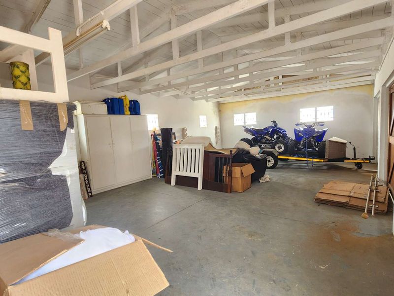 Spacious garage featuring exposed timber roof trusses, concrete flooring, and built-in storage cabinetry, offering ample room for vehicle parking and workshop use.
