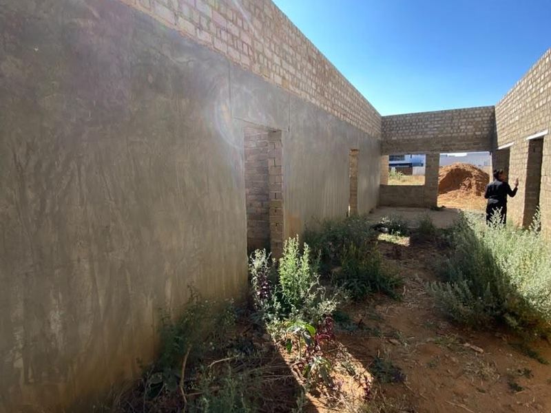 An unfinished construction site showing exposed brick and cement rendered walls, representing a property in the early stages of development.