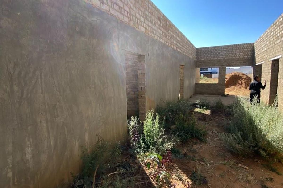 An unfinished construction site showing exposed brick and cement rendered walls, representing a property in the early stages of development.