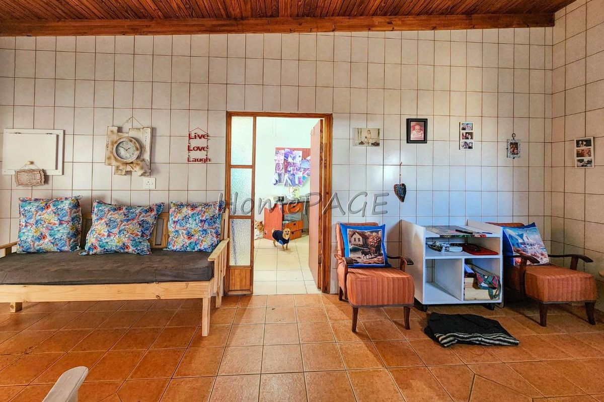 Living area featuring tiled flooring, tiled wall finishes, and a timber ceiling, providing a dated interior space with potential for modernization.