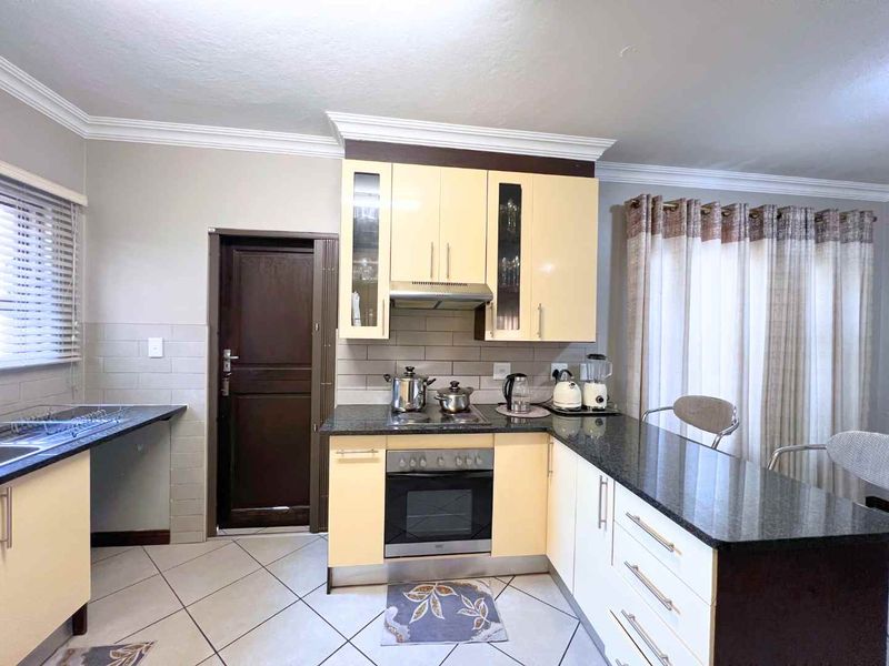 Functional kitchen featuring granite countertops, built-in oven with hob, extractor fan, and ample cabinetry with a tiled backsplash.