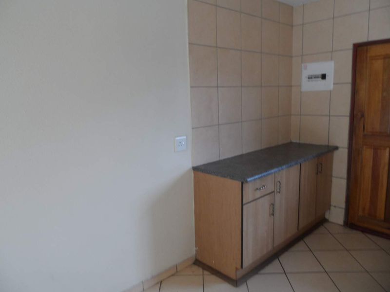 A compact kitchen area featuring built-in cabinetry, a laminate countertop, tiled splashback, and tiled flooring.