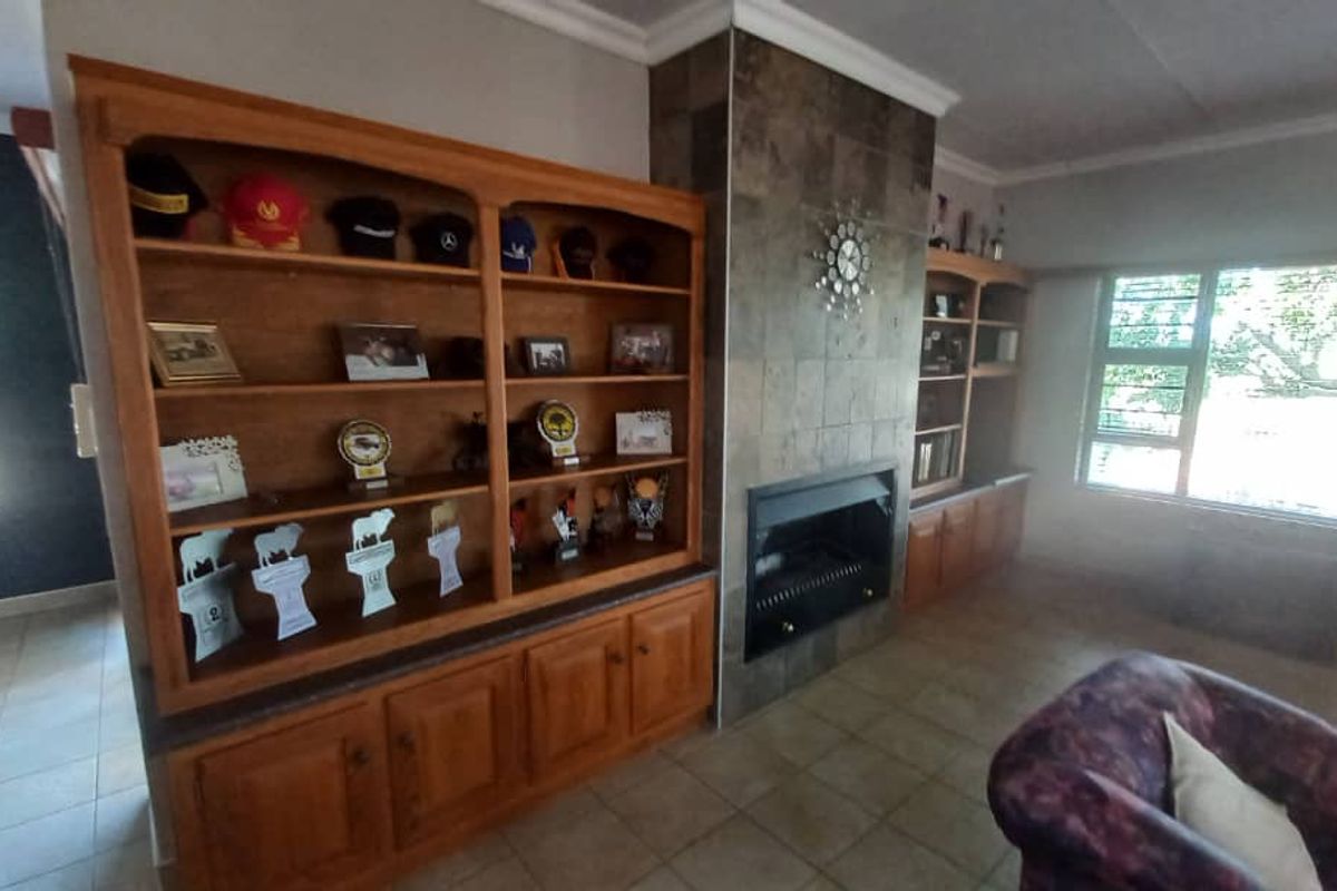 Spacious living room featuring a prominent tiled fireplace and extensive built-in wooden cabinetry, offering ample storage and a warm, traditional aesthetic.