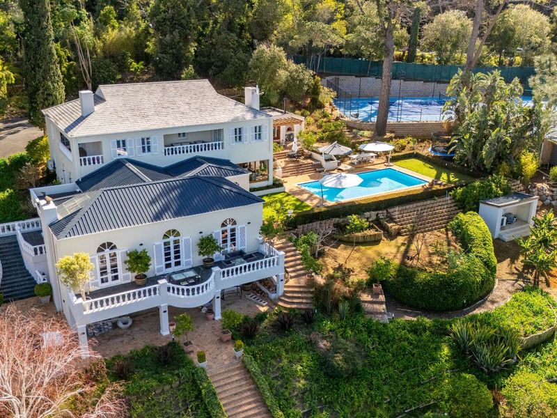 Aerial view of a large residential property featuring a swimming pool, tennis court, multi-level terraces, and extensive landscaped gardens.