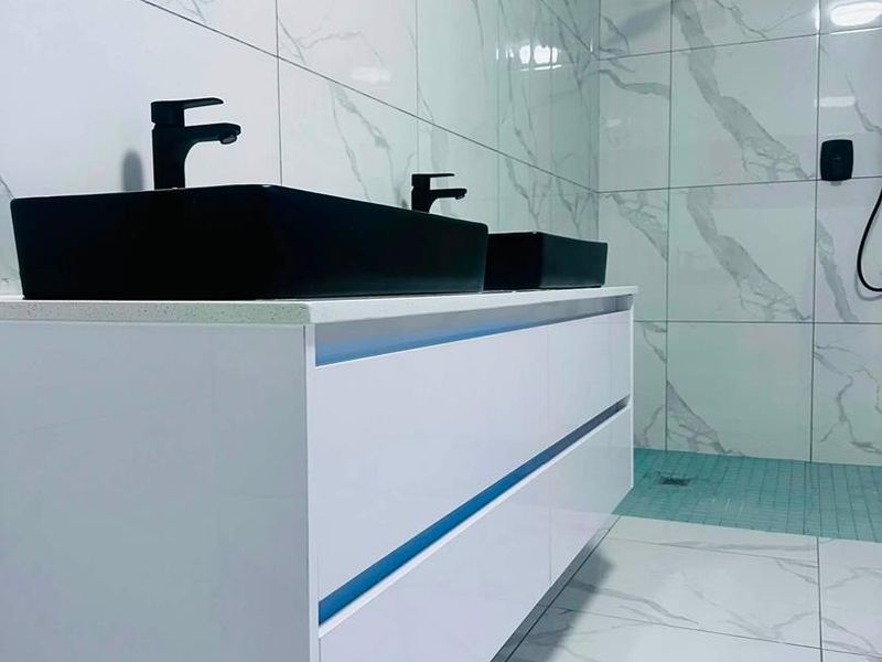 Modern bathroom featuring a sleek double vanity with black vessel sinks, marble-effect tiling, and a contemporary walk-in shower with matte black fixtures.