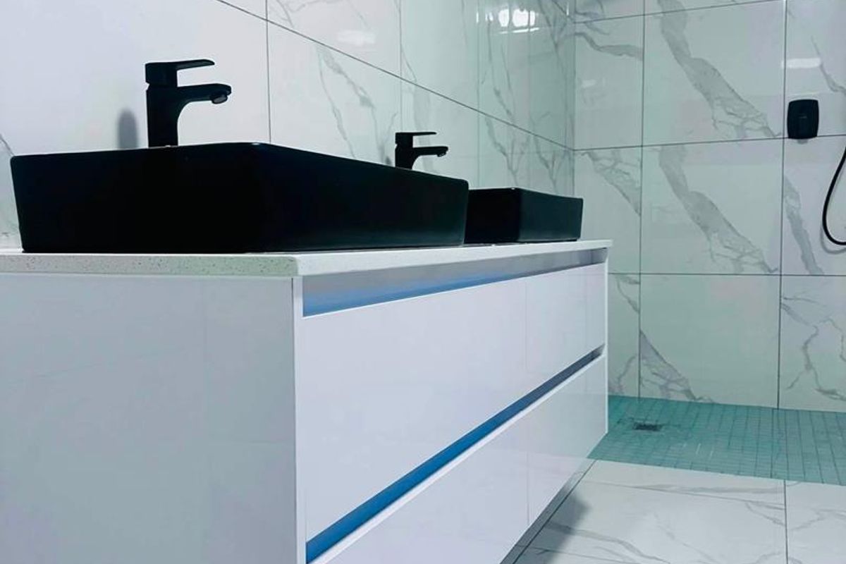 Modern bathroom featuring a sleek double vanity with black vessel sinks, marble-effect tiling, and a contemporary walk-in shower with matte black fixtures.