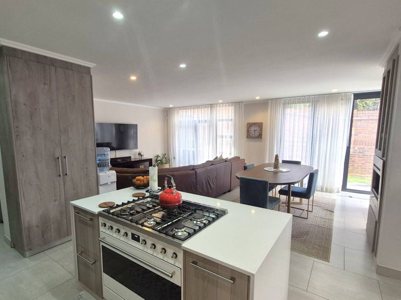 Spacious open-plan living area featuring a modern kitchen with a gas hob, island, and seamless flow to the dining and lounge space with garden access.
