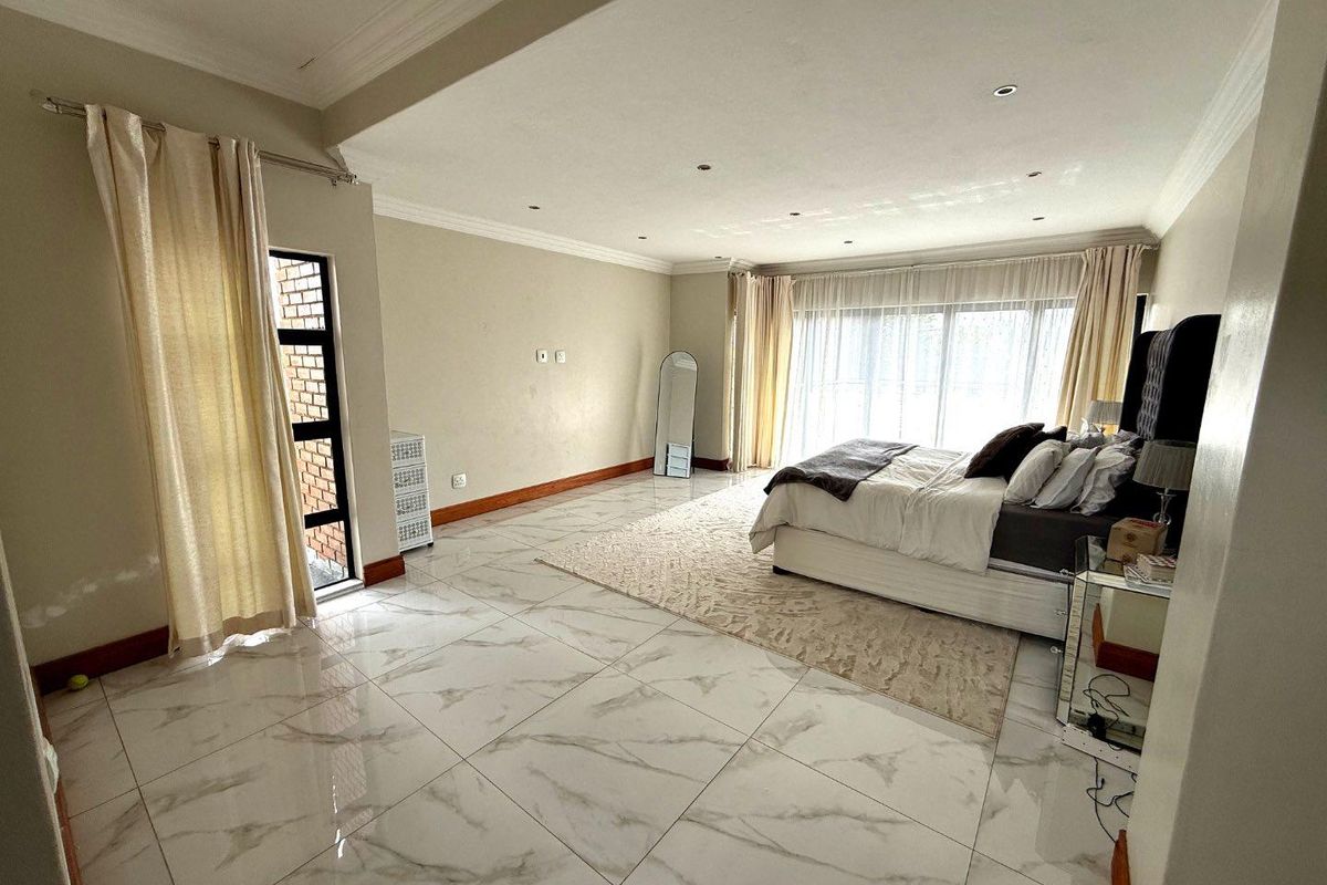 Spacious bedroom featuring large format marble-look floor tiles, recessed ceiling lighting, and sliding glass doors providing ample natural light.