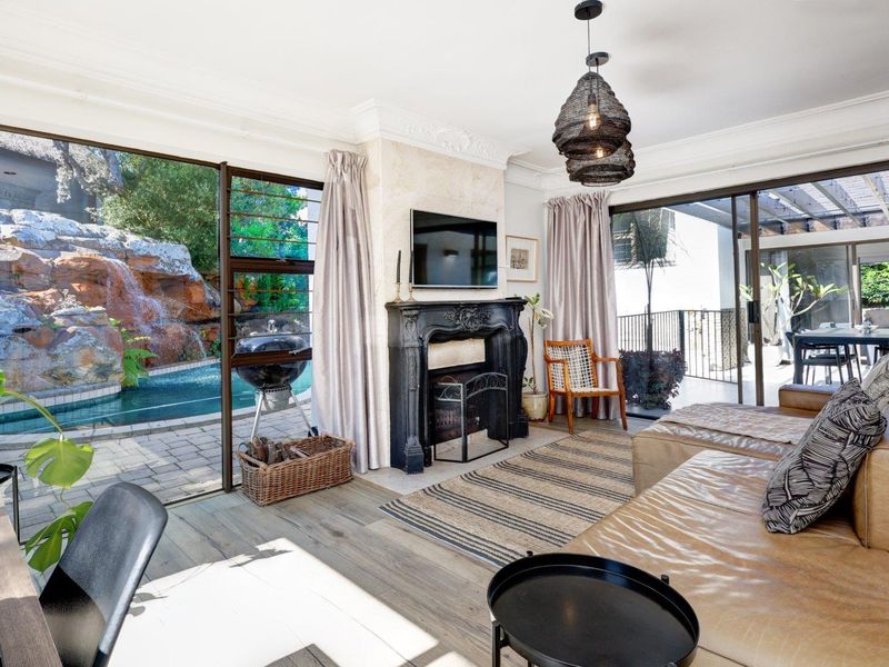 Spacious living room featuring an ornate fireplace, crown molding, and large sliding glass doors providing seamless access to the pool area and patio.