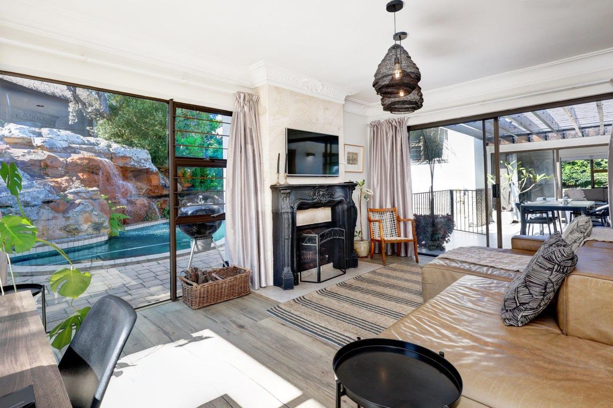 Spacious living room featuring an ornate fireplace, crown molding, and large sliding glass doors providing seamless access to the pool area and patio.