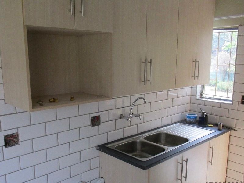 A functional kitchen area featuring light-toned cabinetry, a double bowl stainless steel sink, and a classic white subway tile backsplash.