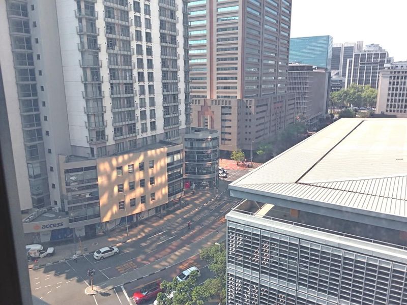 An elevated urban view overlooking a busy city street surrounded by high-rise commercial office buildings and modern architectural facades.