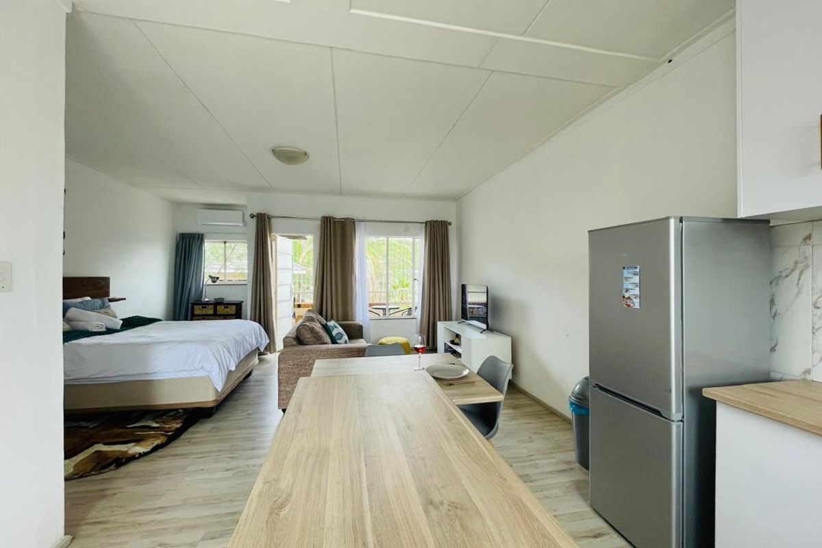 Open-plan studio apartment featuring a combined living, sleeping, and kitchen area with light wood-look flooring and modern cabinetry.