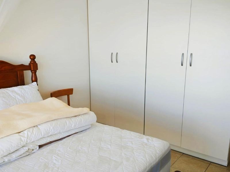 A bedroom featuring neutral walls, tiled flooring, and ample built-in cupboard storage.