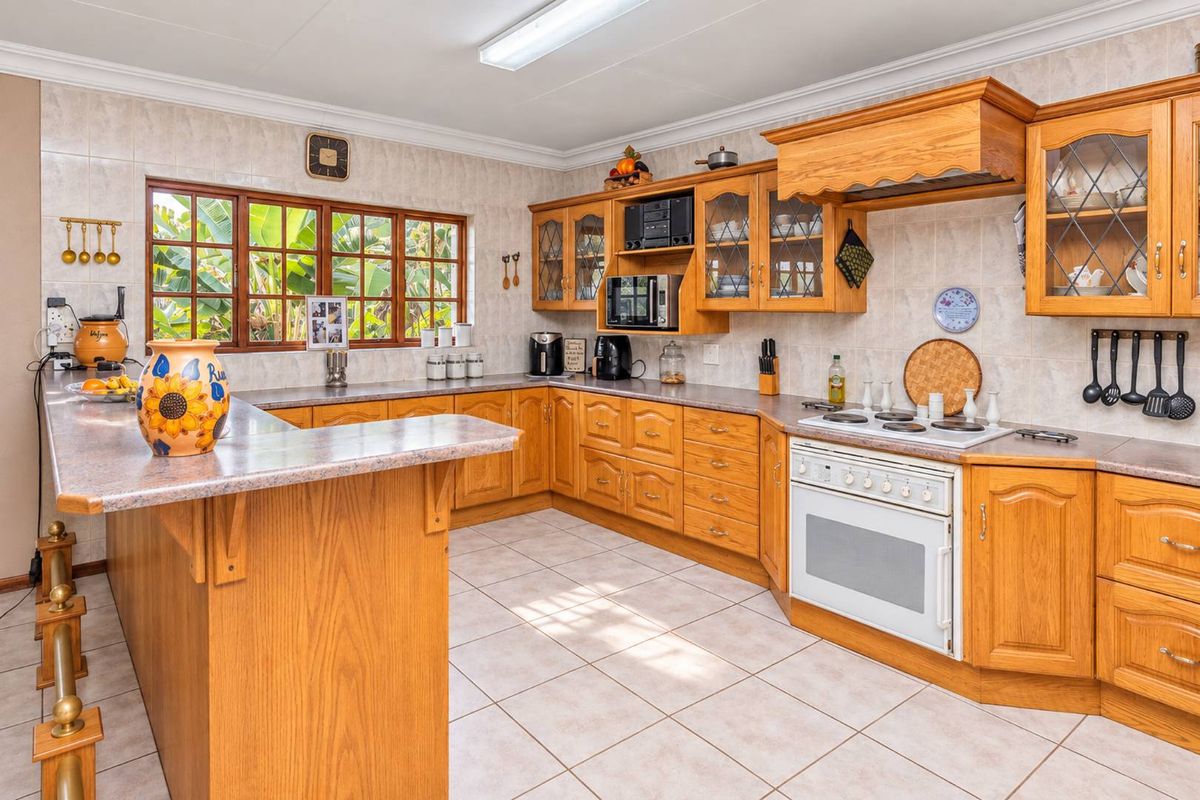 A spacious kitchen featuring traditional wooden cabinetry, laminate countertops, a breakfast bar, and built-in cooking appliances with tiled flooring and backsplash.