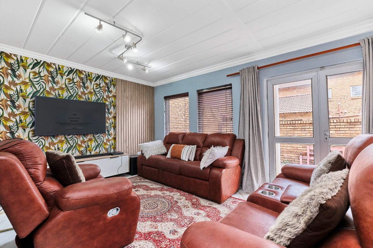 A comfortable living room featuring a decorative accent wall, track lighting, and glass door access to the exterior.