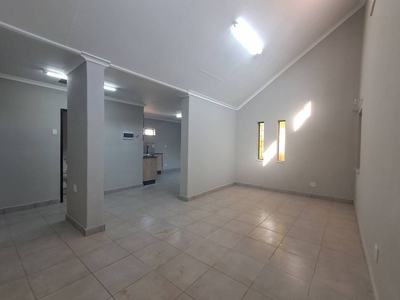 Spacious open-plan living area featuring vaulted ceilings, tiled flooring, and a view into the adjacent kitchen space.