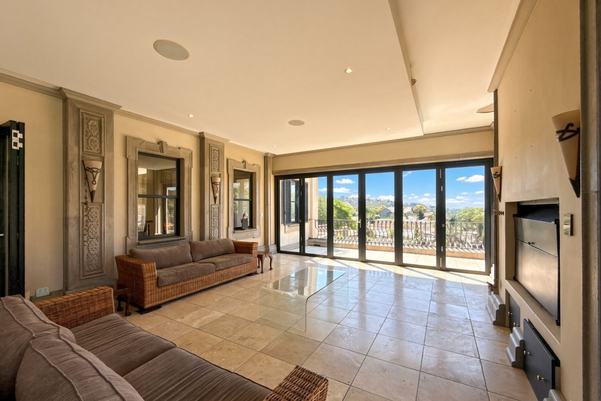 Spacious living room featuring travertine flooring, decorative stone wall detailing, a built-in fireplace, and large bi-fold doors opening to a balcony with scenic views.