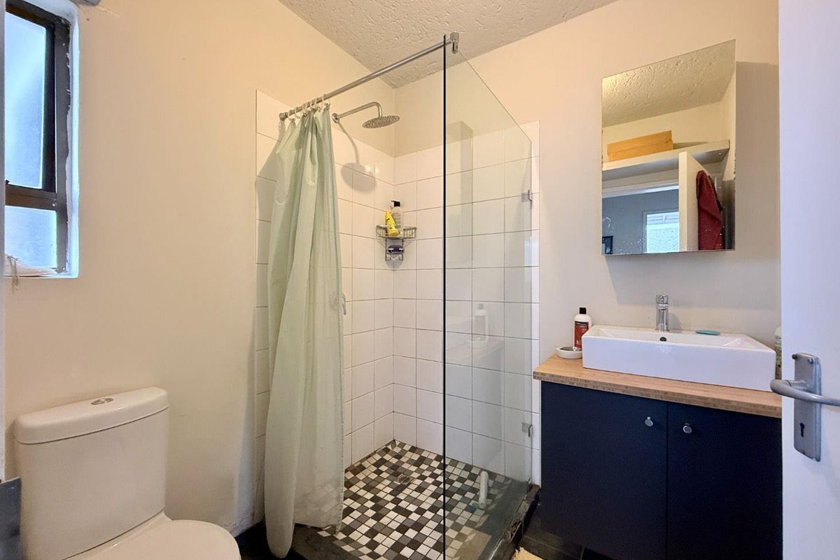 A functional bathroom featuring a walk-in shower with glass screen, modern vanity with vessel sink, and a standard toilet.