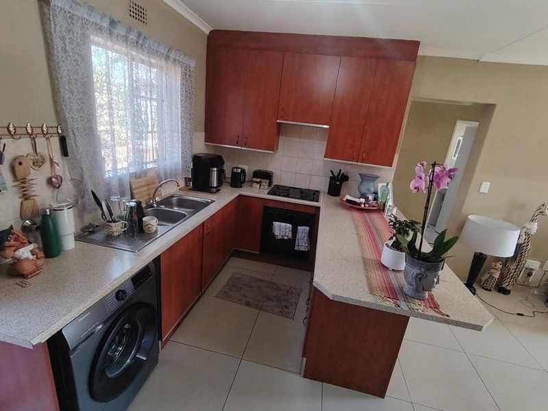 A functional kitchen featuring wood-tone cabinetry, stone-look countertops, a breakfast bar, and integrated appliances, offering a practical layout for daily use.