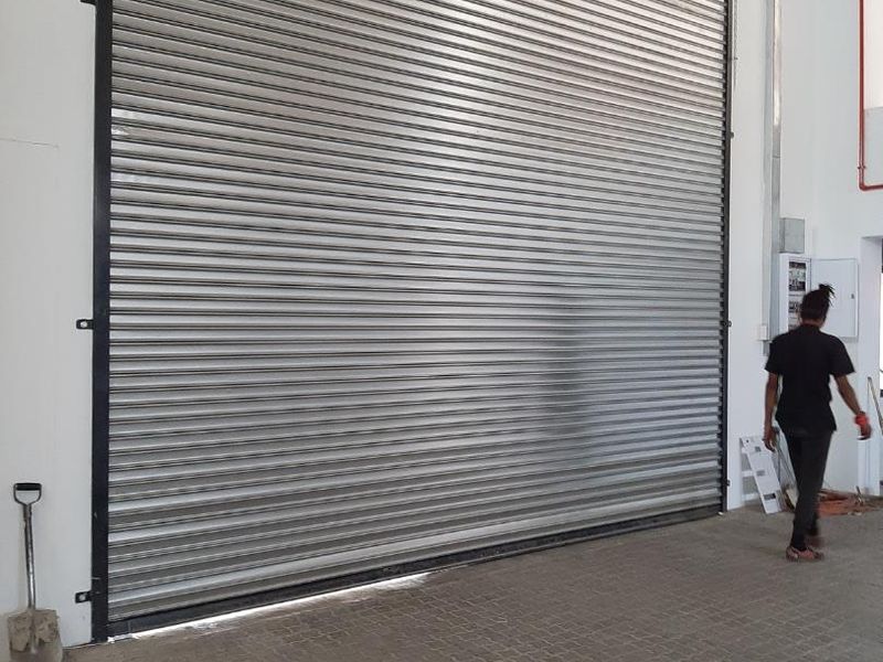Industrial space featuring a large metal roller shutter door and durable paved flooring, suitable for warehouse or workshop operations.
