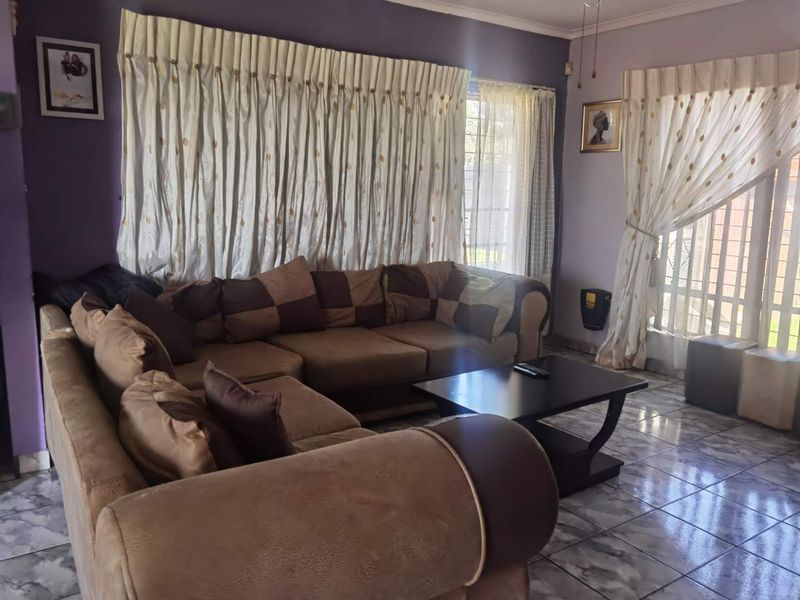 A living room featuring tiled flooring, a wall-mounted heater, and access to the exterior through a sliding glass door.