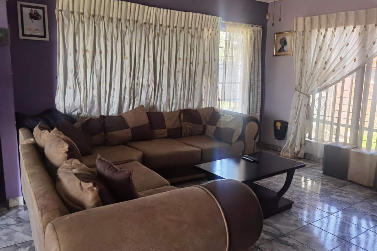 A living room featuring tiled flooring, a wall-mounted heater, and access to the exterior through a sliding glass door.