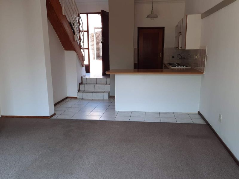 Open plan living area featuring a kitchen with breakfast bar, tiled flooring, and a staircase leading to the upper level.