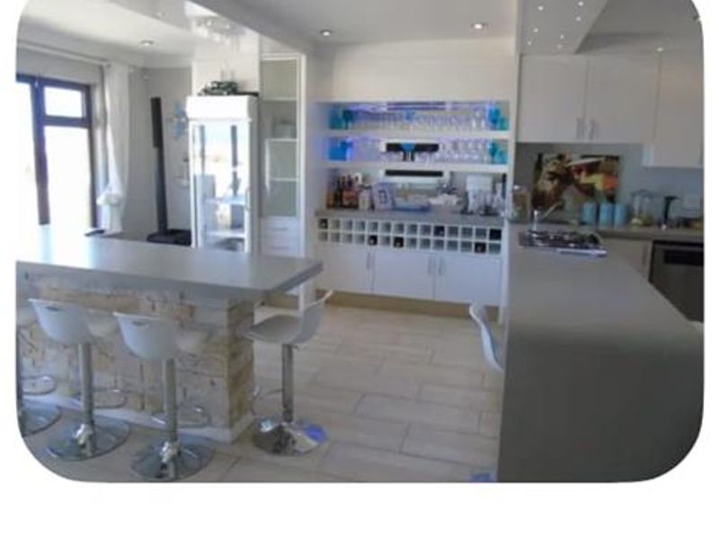 A modern entertainment area featuring a built-in bar with stone cladding, integrated wine storage, and stylish recessed lighting.