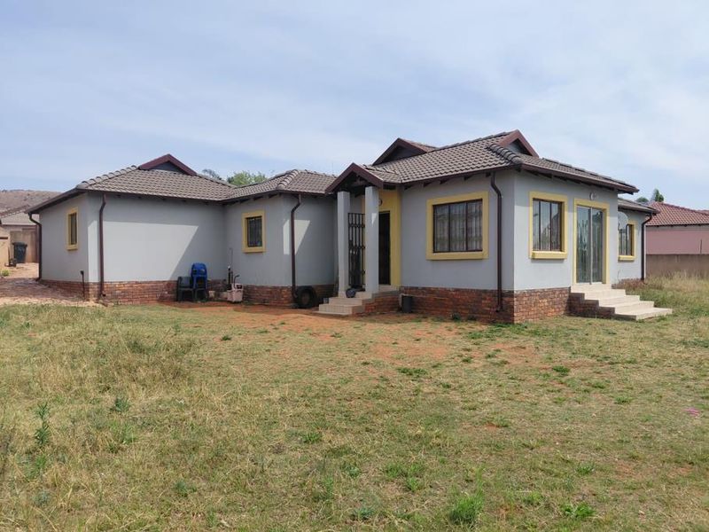 Rear view of a single-story house featuring a tiled roof, brick base, and sliding door access to the yard.