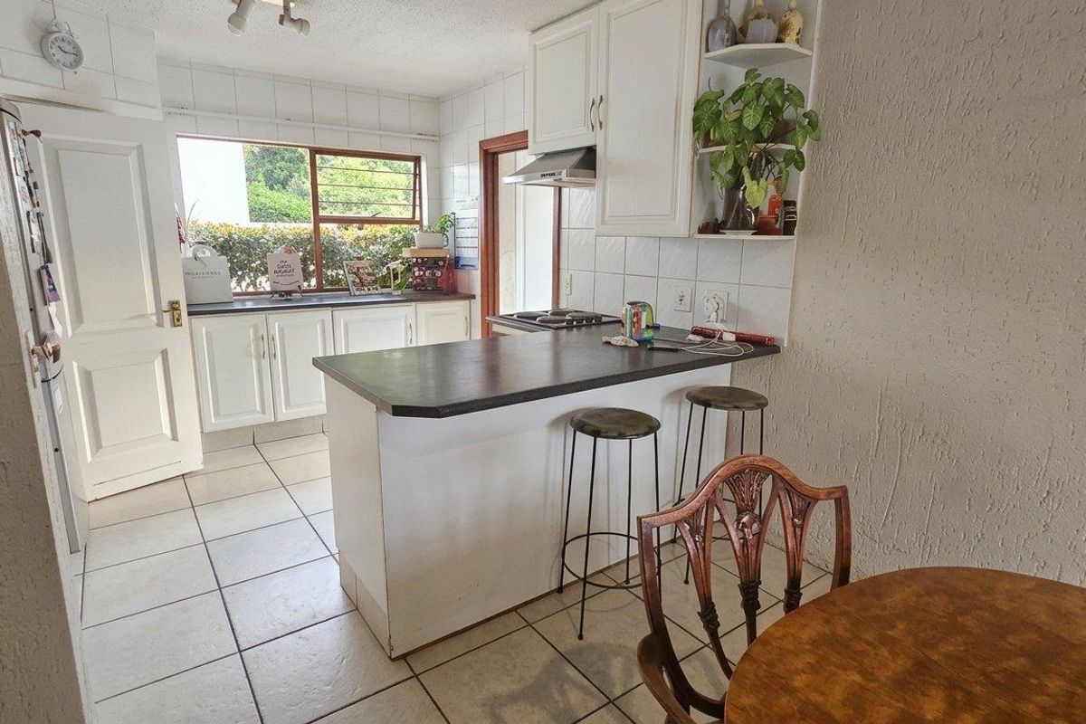 A functional kitchen featuring white cabinetry, a breakfast bar, tiled backsplash, and tiled flooring, offering a practical layout for daily meal preparation.