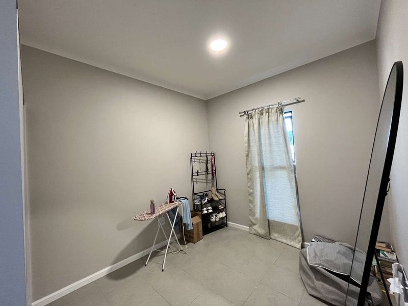 A neutral-toned bedroom featuring tiled flooring and recessed ceiling lighting, offering a clean and versatile space ready for personalization.