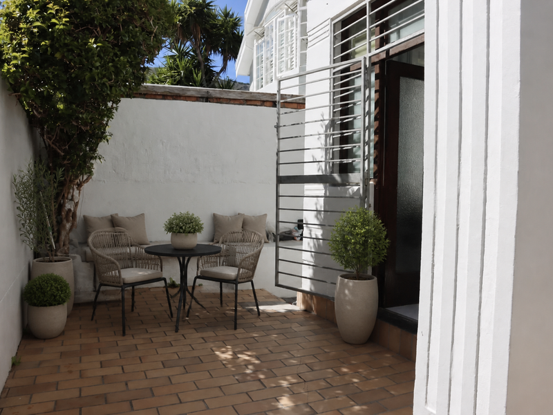 A private outdoor patio area featuring brick paving, a built-in bench, and a secure metal gate entrance to the apartment.