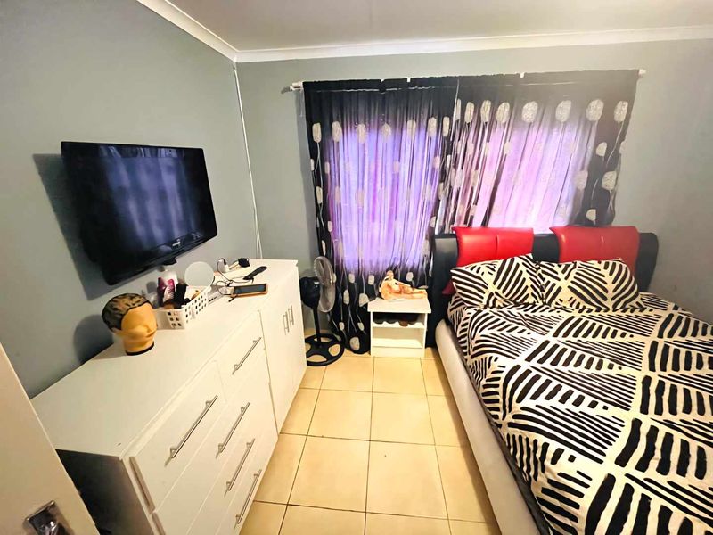 A standard bedroom featuring tiled flooring and cove cornice detailing, providing a functional space for rest.