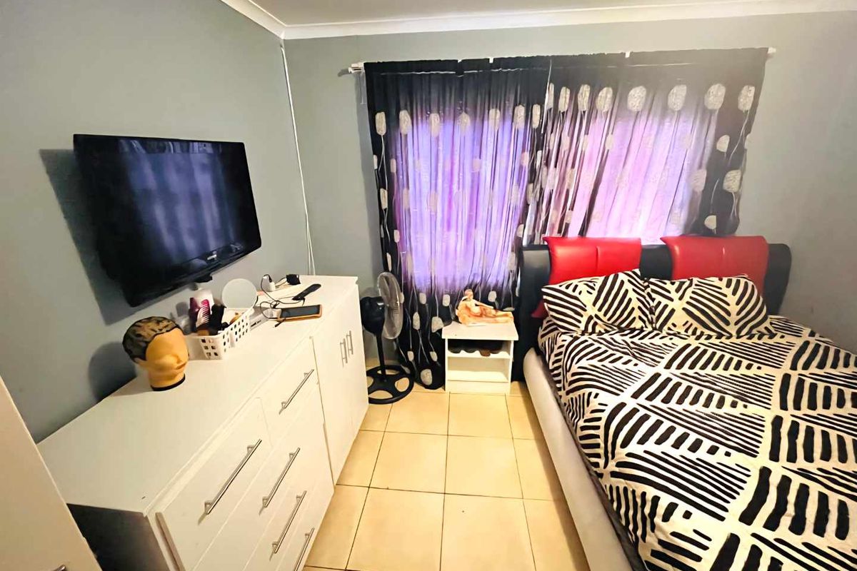 A standard bedroom featuring tiled flooring and cove cornice detailing, providing a functional space for rest.