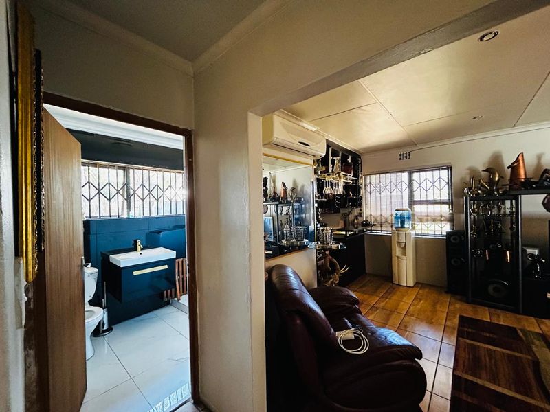 Open plan living area featuring tiled floors and air conditioning, with an adjacent bathroom containing a modern vanity and toilet.