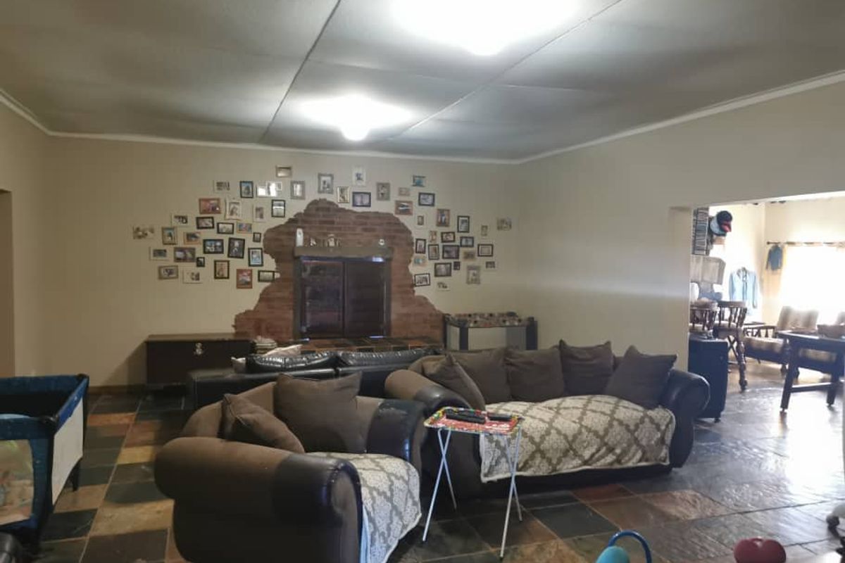 Spacious living area featuring a prominent brick-accented fireplace and durable slate-style floor tiling, offering a comfortable and rustic atmosphere.