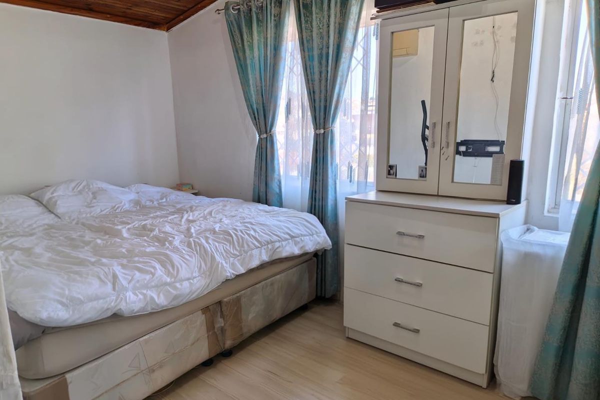 A bedroom featuring a timber-paneled ceiling, laminate flooring, and security bars on the windows.
