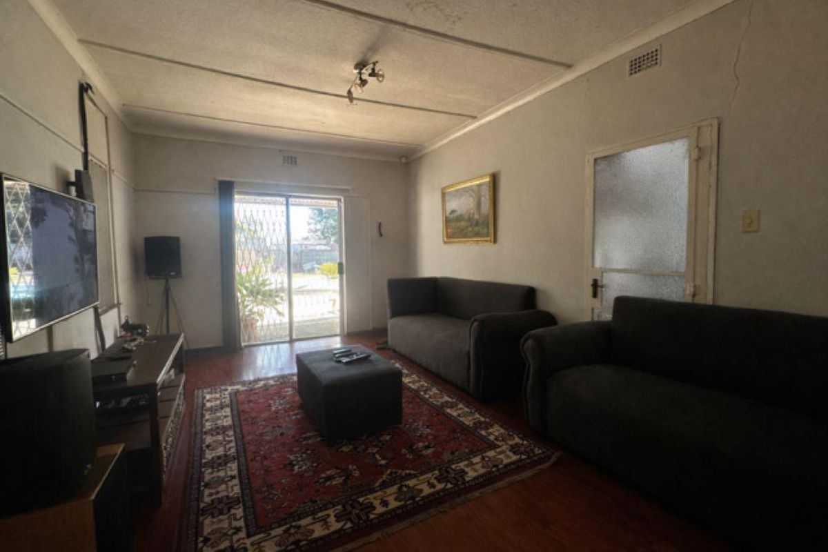 A living room featuring wood-look flooring, a sliding glass door with security gate, and access to an outdoor area.