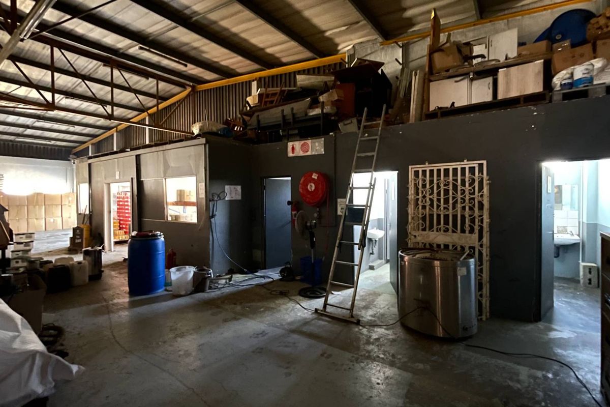Industrial utility space featuring exposed steel roof trusses, concrete flooring, and partitioned office or storage areas with integrated fire safety equipment.