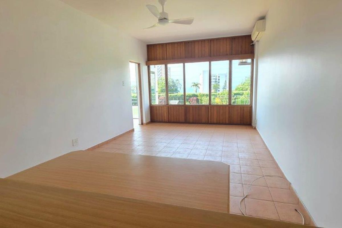 An empty living room featuring tiled flooring, a ceiling fan, and large timber-framed windows providing natural light and exterior views.